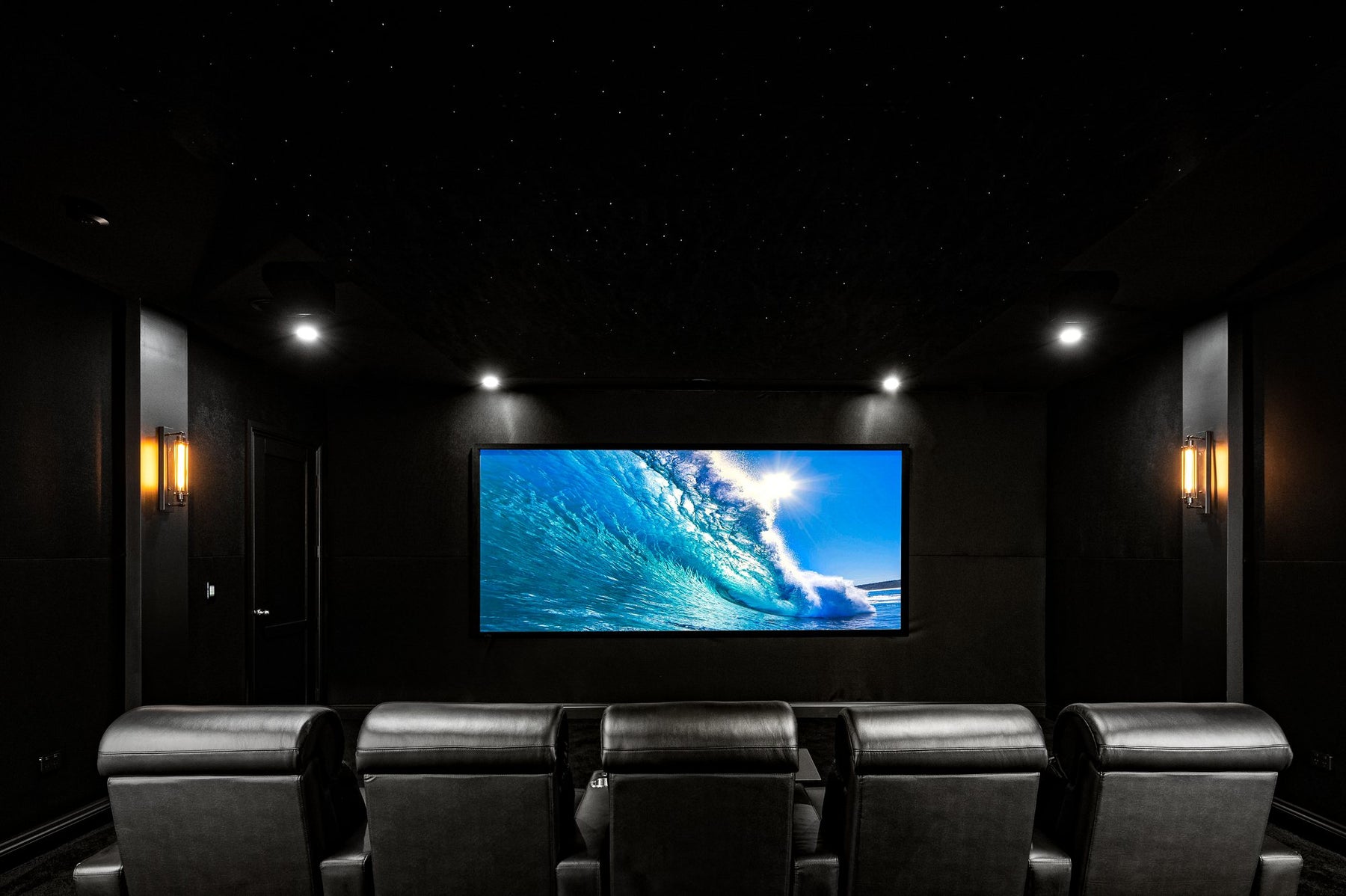 A blacked-out dedicated home cinema with a cinemascope screen and fibre-optic star ceiling.